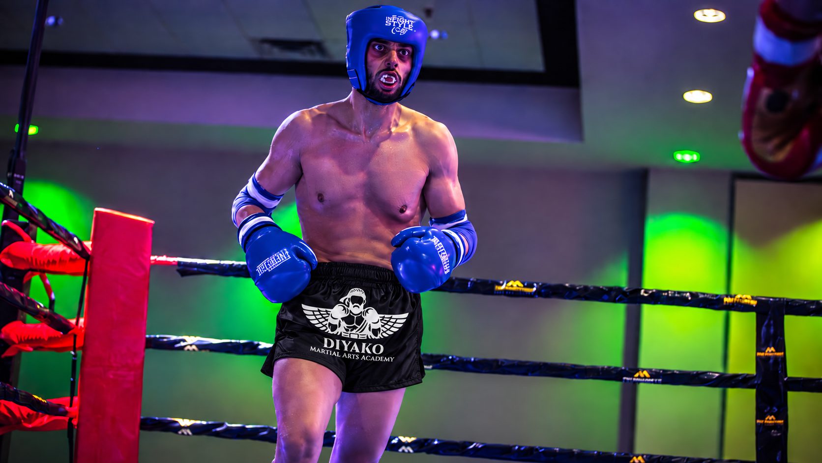 DKM fighter in DIYAKO shorts celebrating inside the ring under fight-night lights